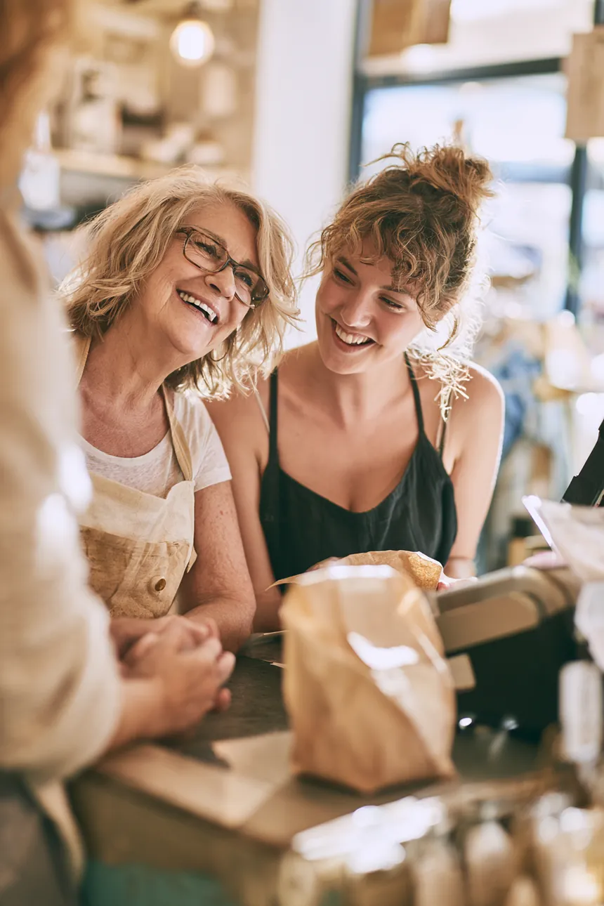 Customer chatting warmly with a shop owner at a modern checkout counter